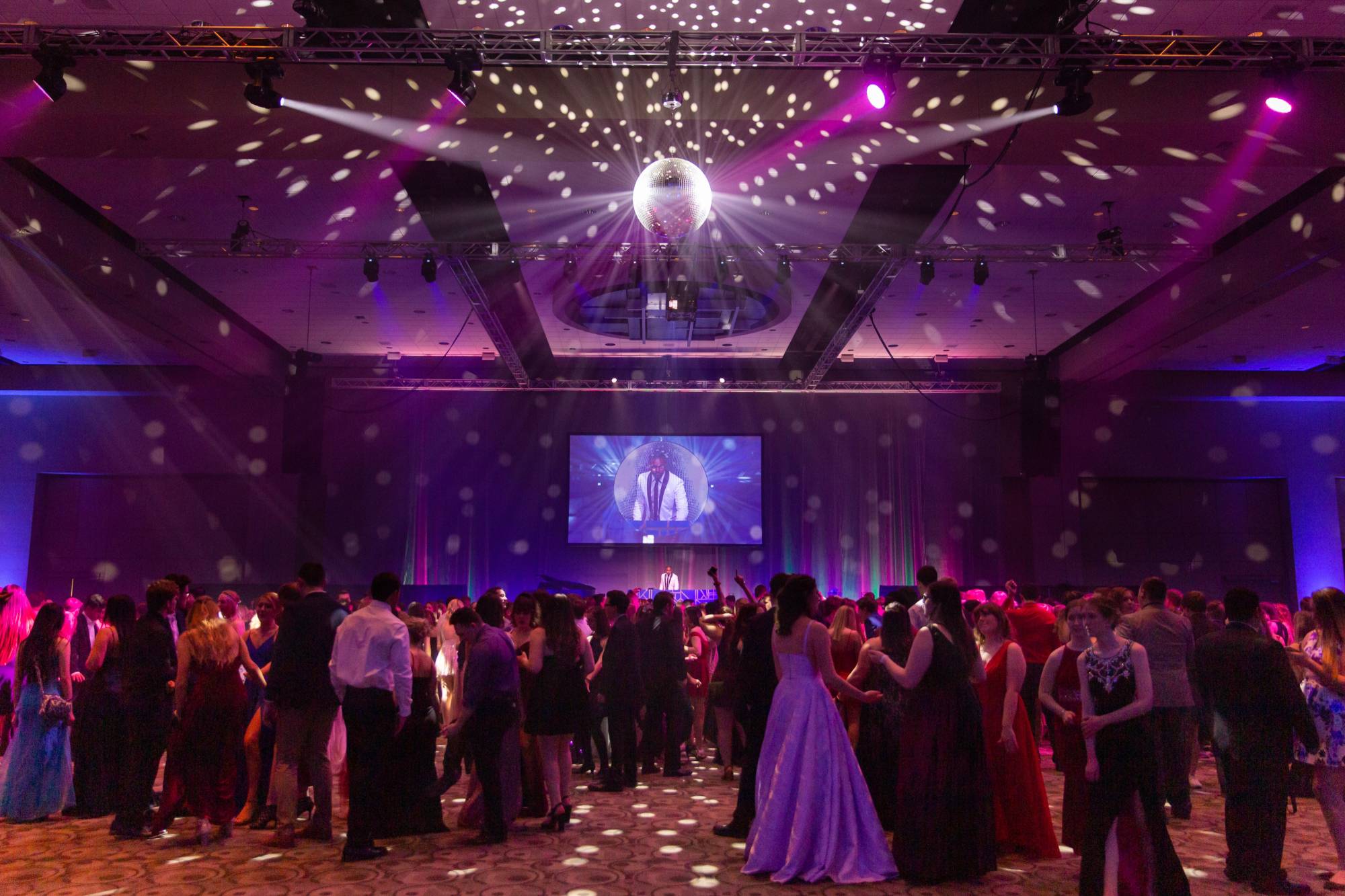 Overview of students dancing at Presidents' Ball with DJ in the background